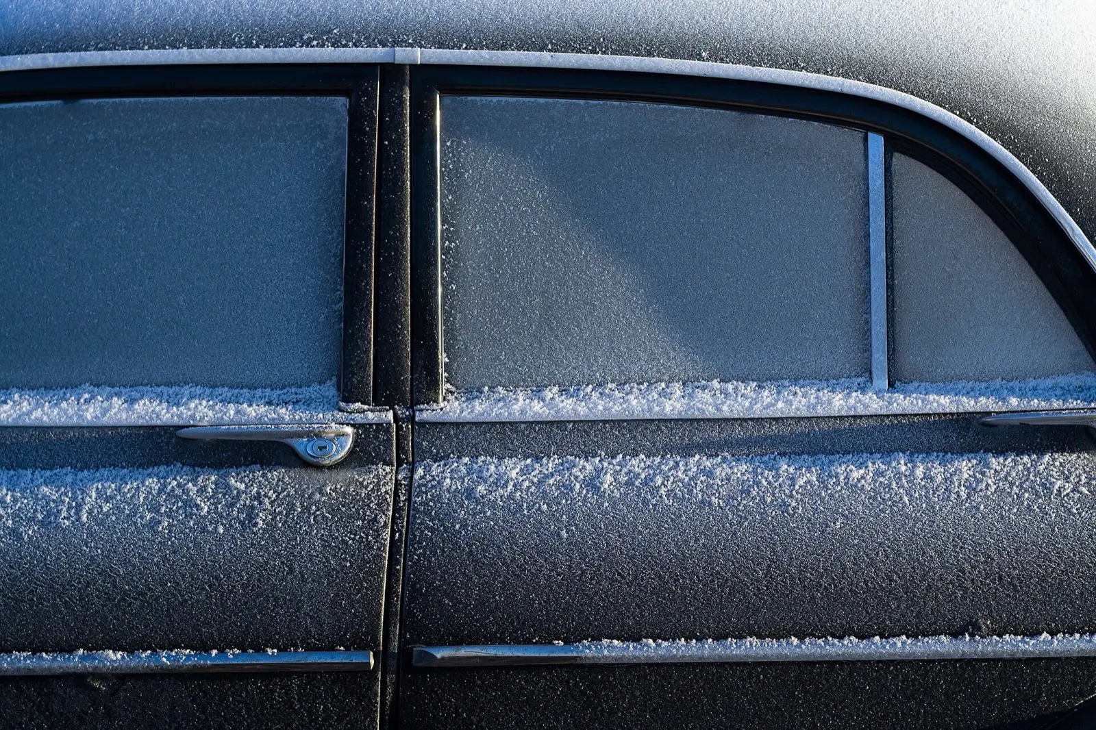 Parkerad svart bil täckt av frost